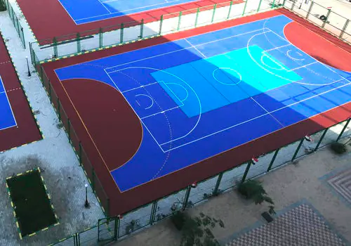 Açık hava spor kompleksinde kırmızı ve mavi akrilik zeminli basketbol sahasının havadan görünümü
