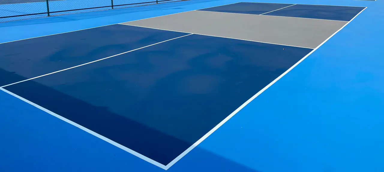 Mavi akrilik kaplamalı tek bir tenis kortunun yüzeyi ve beyaz oyun çizgileri