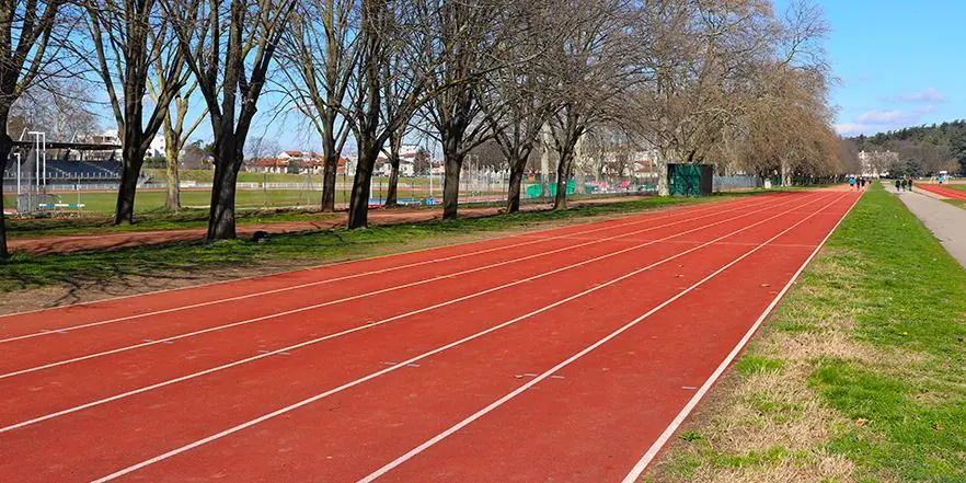 Ağaçlı bir parkta uygulanmış kırmızı EPDM yürüyüş parkuru ve beyaz şerit çizgisi