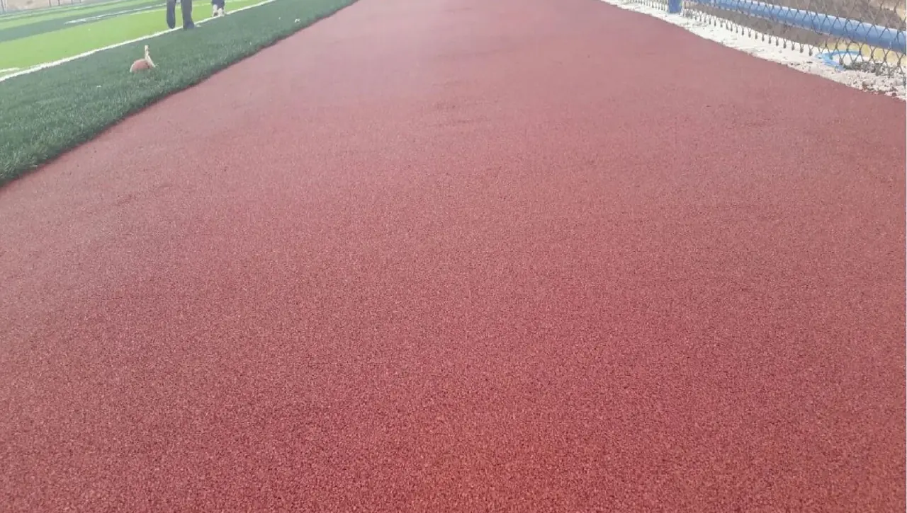 Ağaçlı bir parkta açık havada uygulanmış kırmızı EPDM yürüyüş parkuru