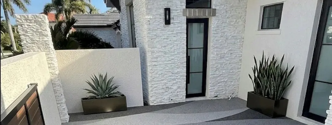 Villa girişinde açık gri taş halı zemin, taş kaplama cephe ve saksı bitkileri