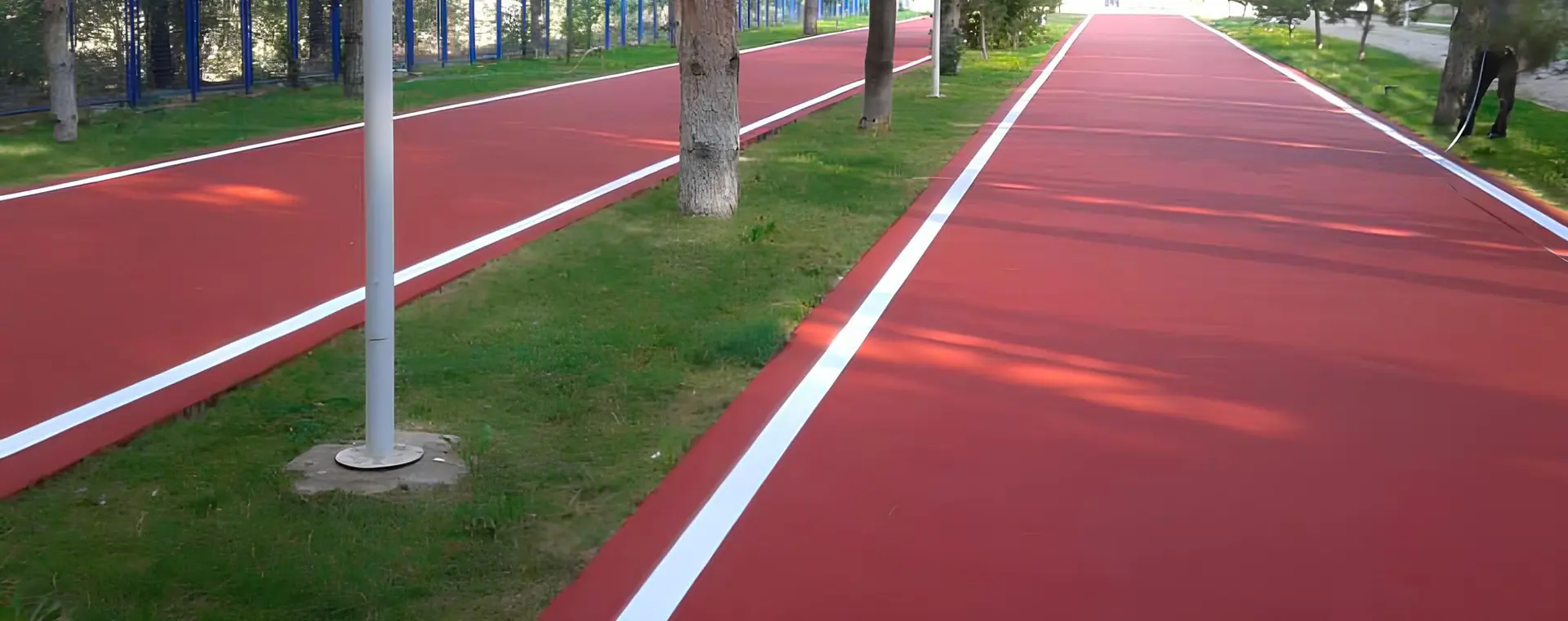 Park içindeki yürüyüş parkurunda uygulanmış kırmızı EPDM zemin ve beyaz şerit çizgileri